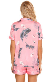 Pink botanical print satin pajama set with buttoned top and shorts.