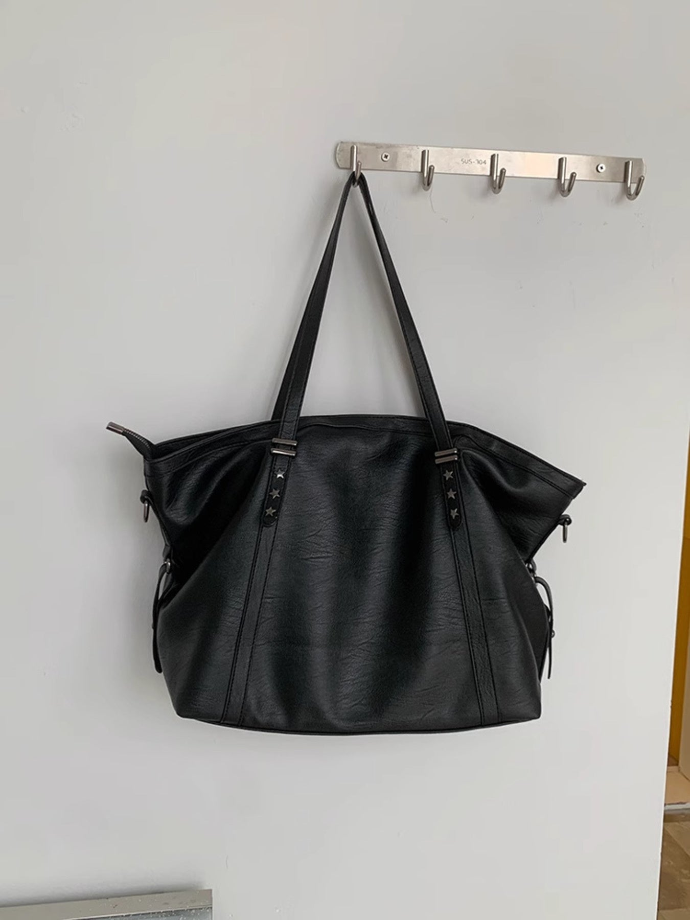 Black pu leather tote bag with star details and double straps.