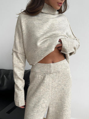 Oversized beige turtleneck lounge knit set with wide leg pants and ribbed cuffs.