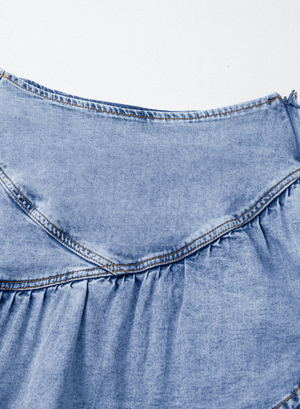 Medium wash denim mini skirt with asymmetrical ruffle detail and contrast stitching.
