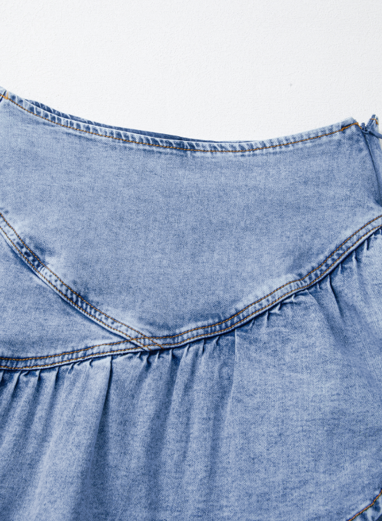 Medium wash denim mini skirt with asymmetrical ruffle detail and contrast stitching.