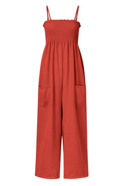 Orange-red smocked bodice palazzo jumpsuit with wide legs and side pockets.