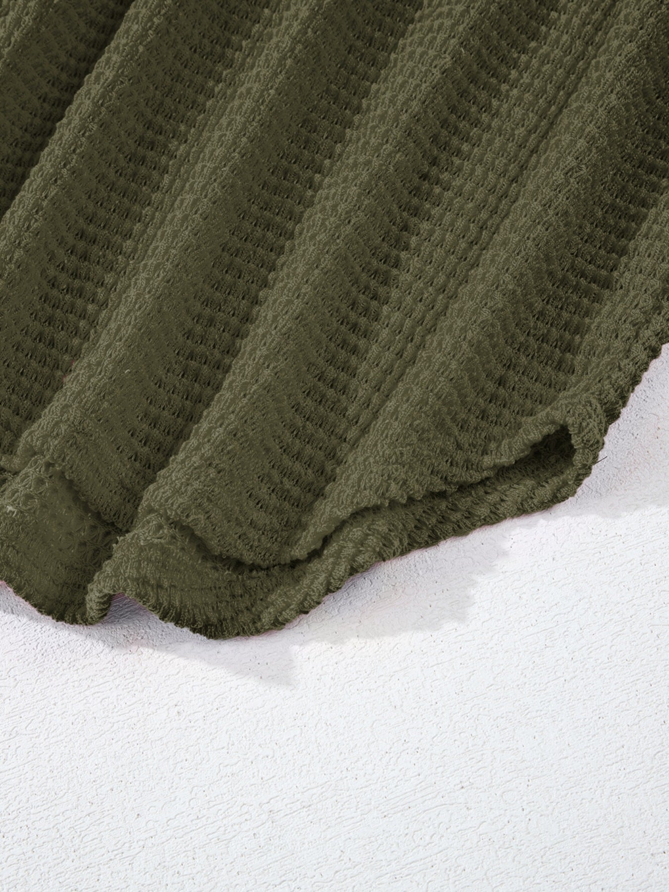Moss green waffle-knit collared shirt with button detail and textured fabric.