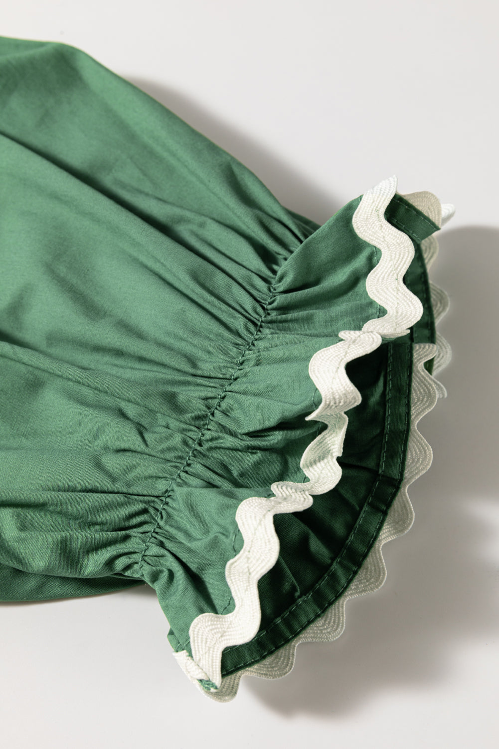 Moss green blouse with ruched puff sleeves and white scalloped trim detail.