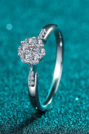 Silver floral cluster moissanite engagement ring with accent stones on band.