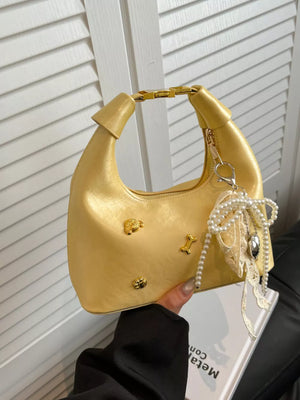 Pastel yellow hobo bag with gold dog and bone charms, pearl and lace embellishments.