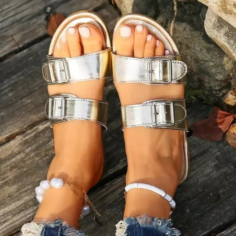 Metallic buckle slide sandals in silver with double straps and adjustable buckles.