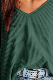 Dark green waffle knit v-neck top with blouson sleeves, shown with a studded belt.
