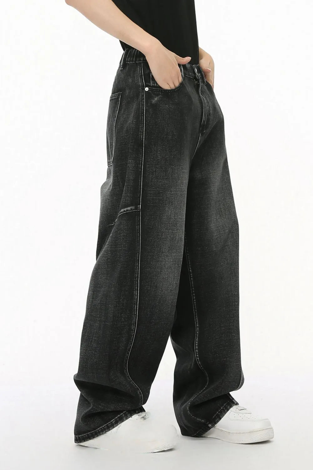 Dark wash denim trousers with exaggerated seam details and a relaxed fit.