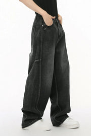 Dark wash denim trousers with exaggerated seam details and a relaxed fit.