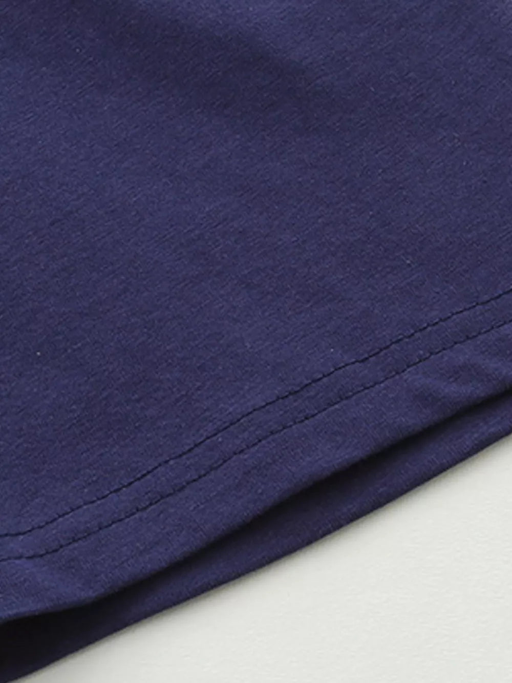 Navy blue cotton baby outfit detail showing stitching.