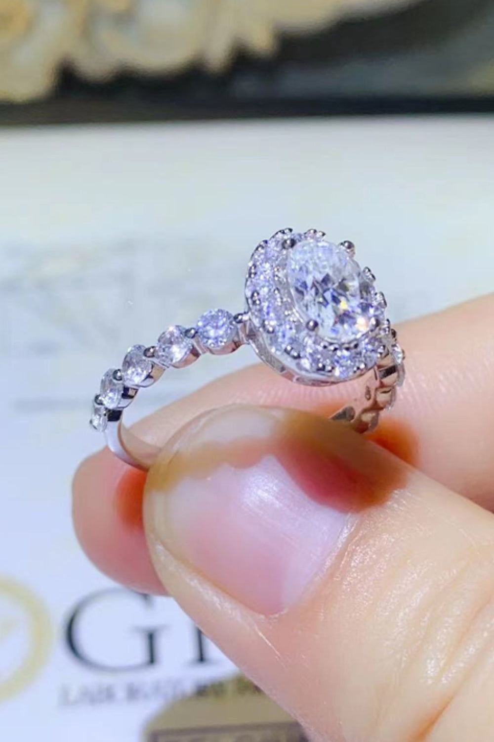 White oval moissanite halo ring with diamond band.