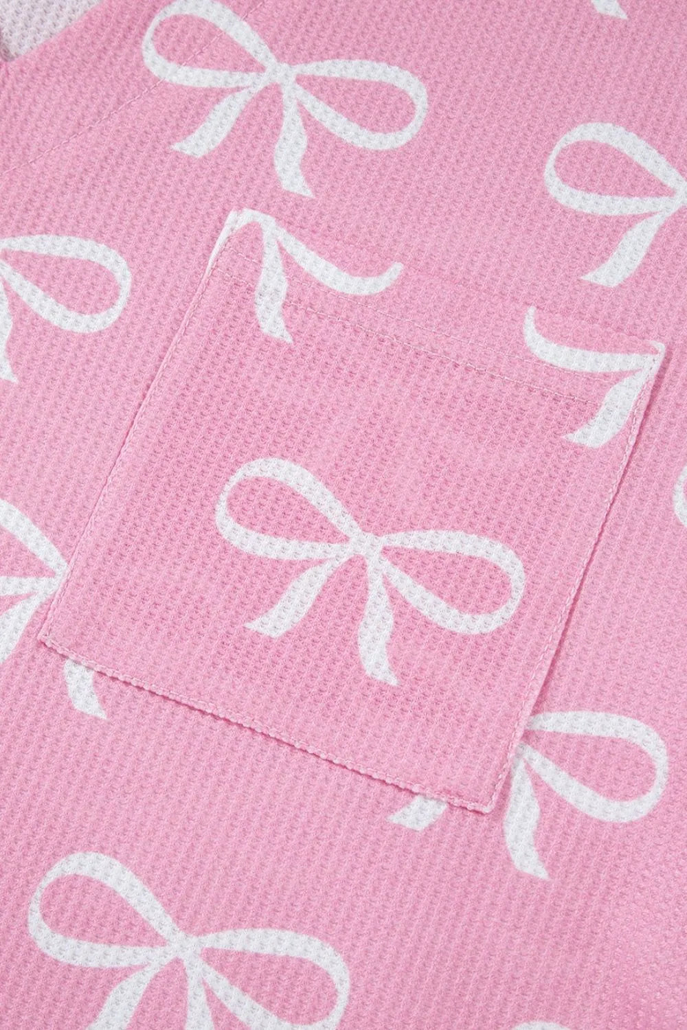Pink ribbed loungewear set with white bow print and a chest pocket detail.