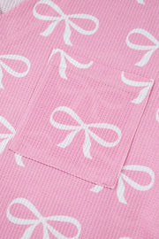 Pink ribbed loungewear set with white bow print and a chest pocket detail.