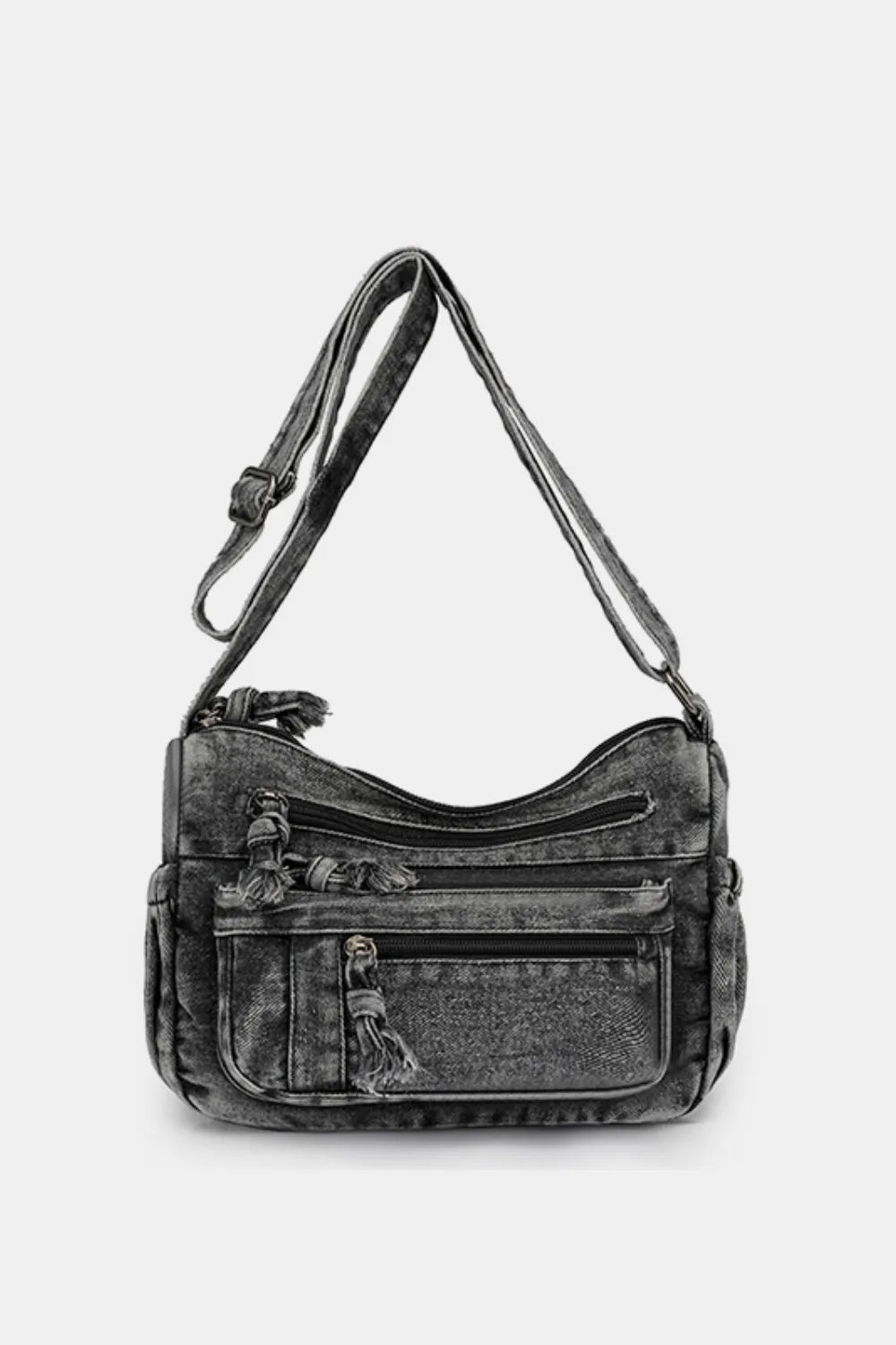 Acid wash denim crossbody bag with multiple zippered pockets and tassel details.