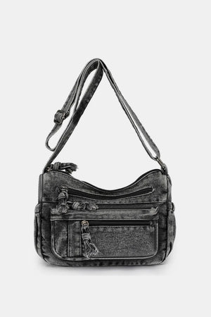 Acid wash denim crossbody bag with multiple zippered pockets and tassel details.