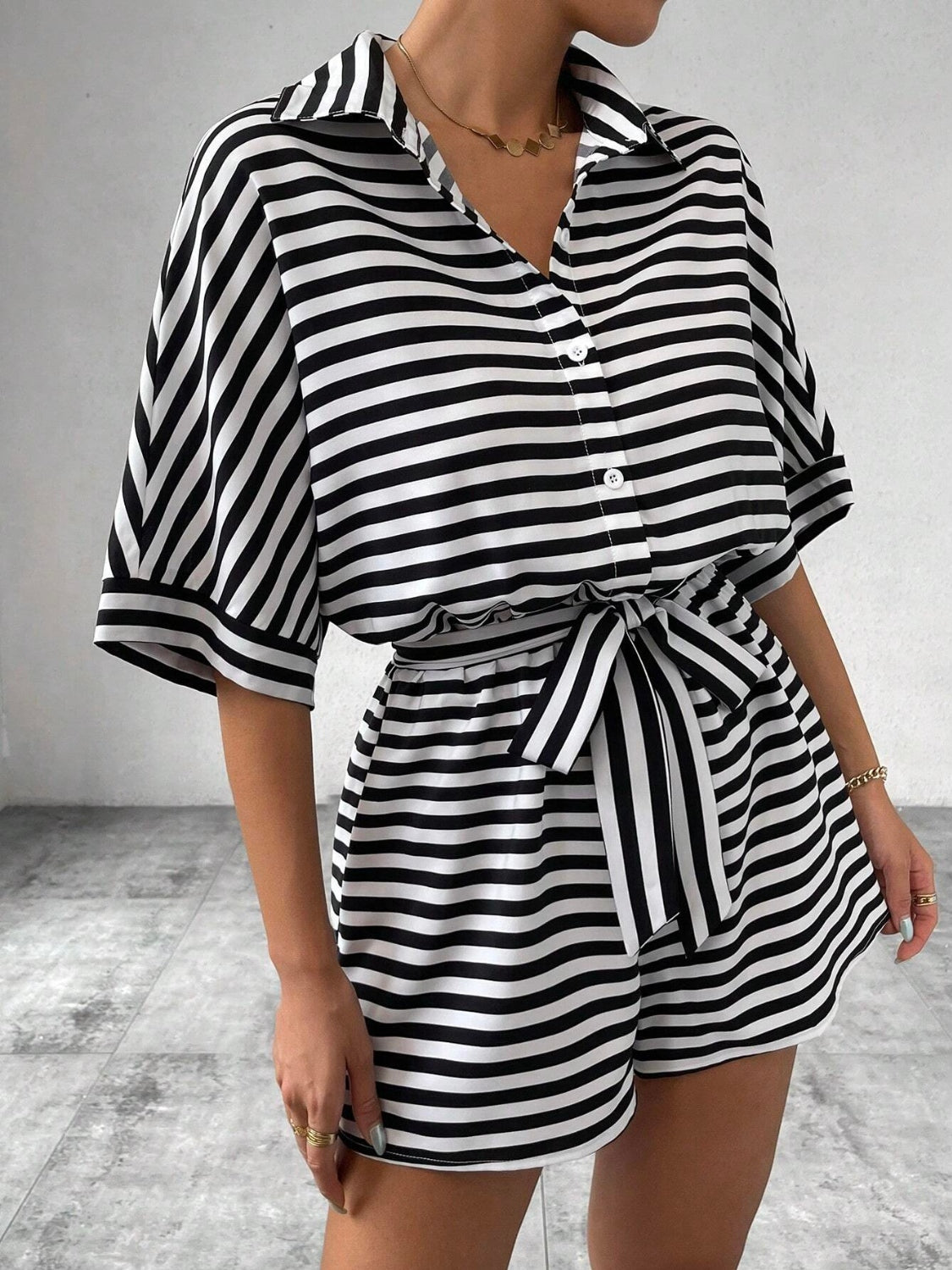Black and white striped shirt romper with self-tie belt and button front.