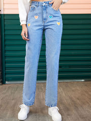 Light wash straight leg jeans with colorful heart patches and button fly.
