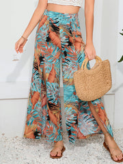 Tropical print palazzo trousers with high slits in multicolor, featuring a wide leg and flowy fabric.