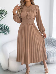 Khaki midi dress with ruffled neckline, smocked waist, and pleated skirt.