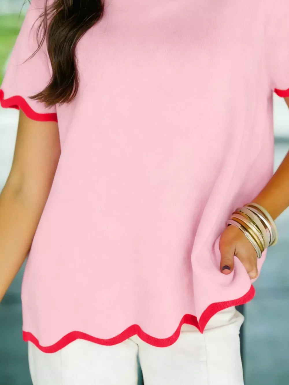 Pink ribbed knit sweater with wavy red trim and short sleeves.