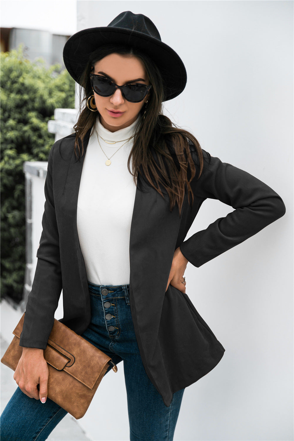 Black drape-front blazer with sculpted silhouette and long sleeves, worn open over a white turtleneck.
