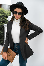 Black drape-front blazer with sculpted silhouette and long sleeves, worn open over a white turtleneck.