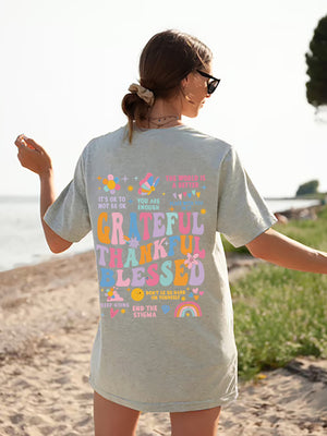 Aqua vintage wash graphic tee with affirmation text and colorful graphics on back