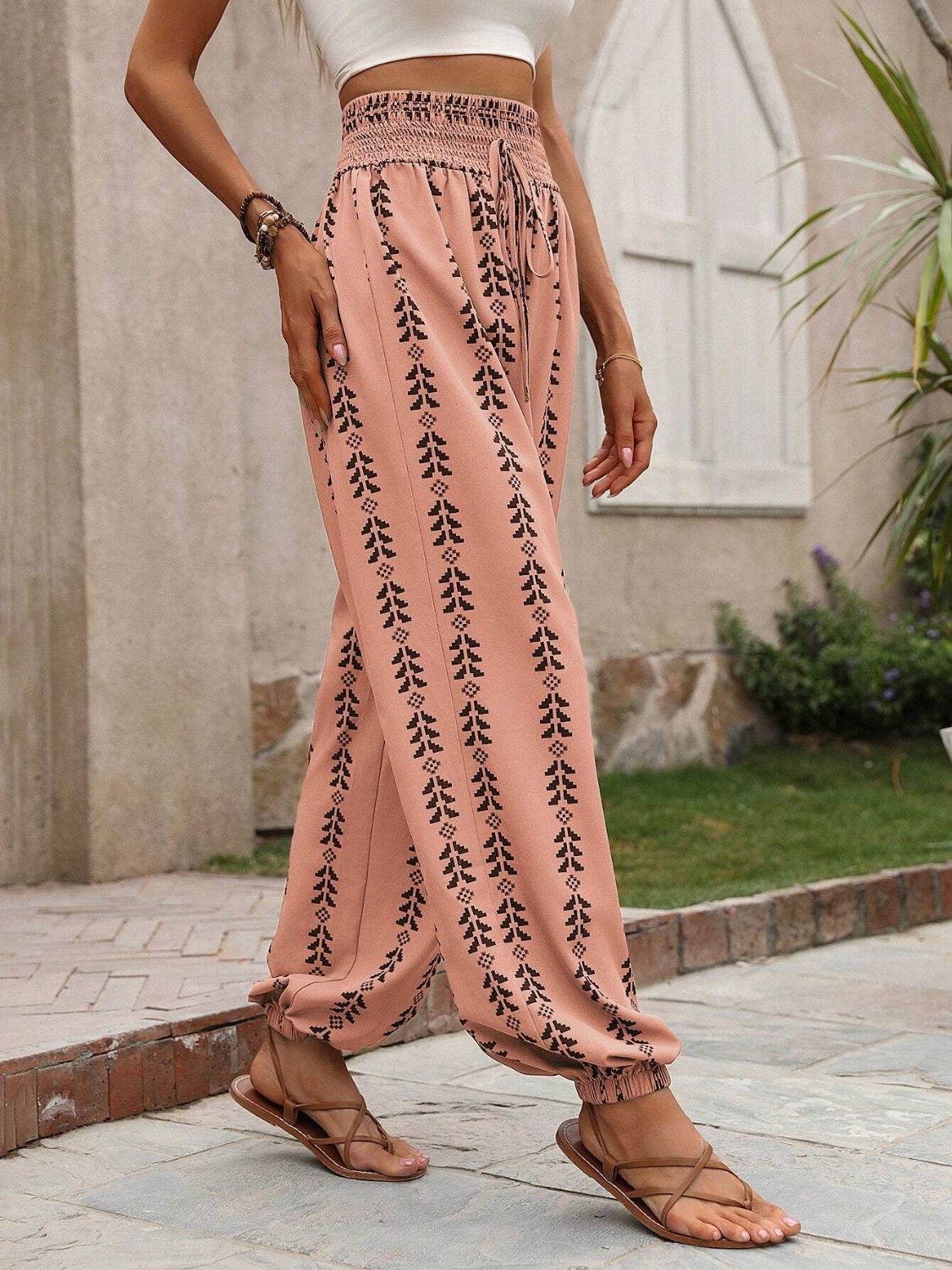 Burnt Coral gathered ankle trousers with black leaf print and drawstring waist.