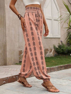 Burnt Coral gathered ankle trousers with black leaf print and drawstring waist.