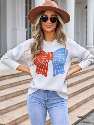 Graphic bow knit sweater in ivory with red and blue bow detail.
