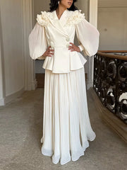 Apricot skirt suit with ruffled collar, peplum jacket, and pleated maxi skirt.