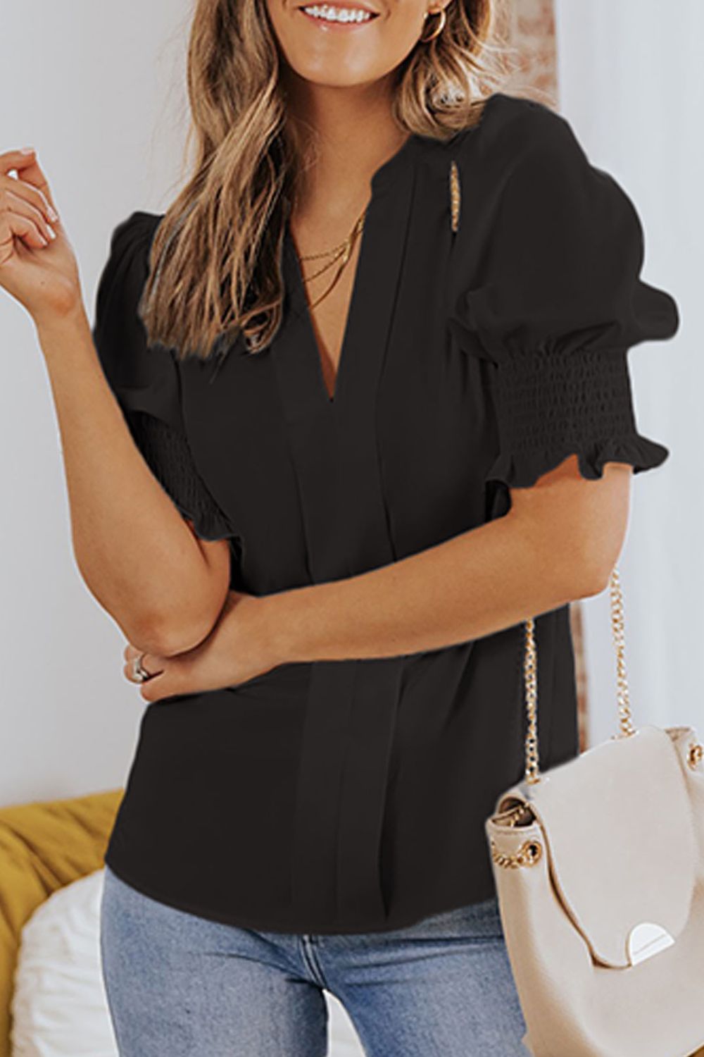 Black puff sleeve v-neck blouse with smocked cuffs and a gold chain detail.