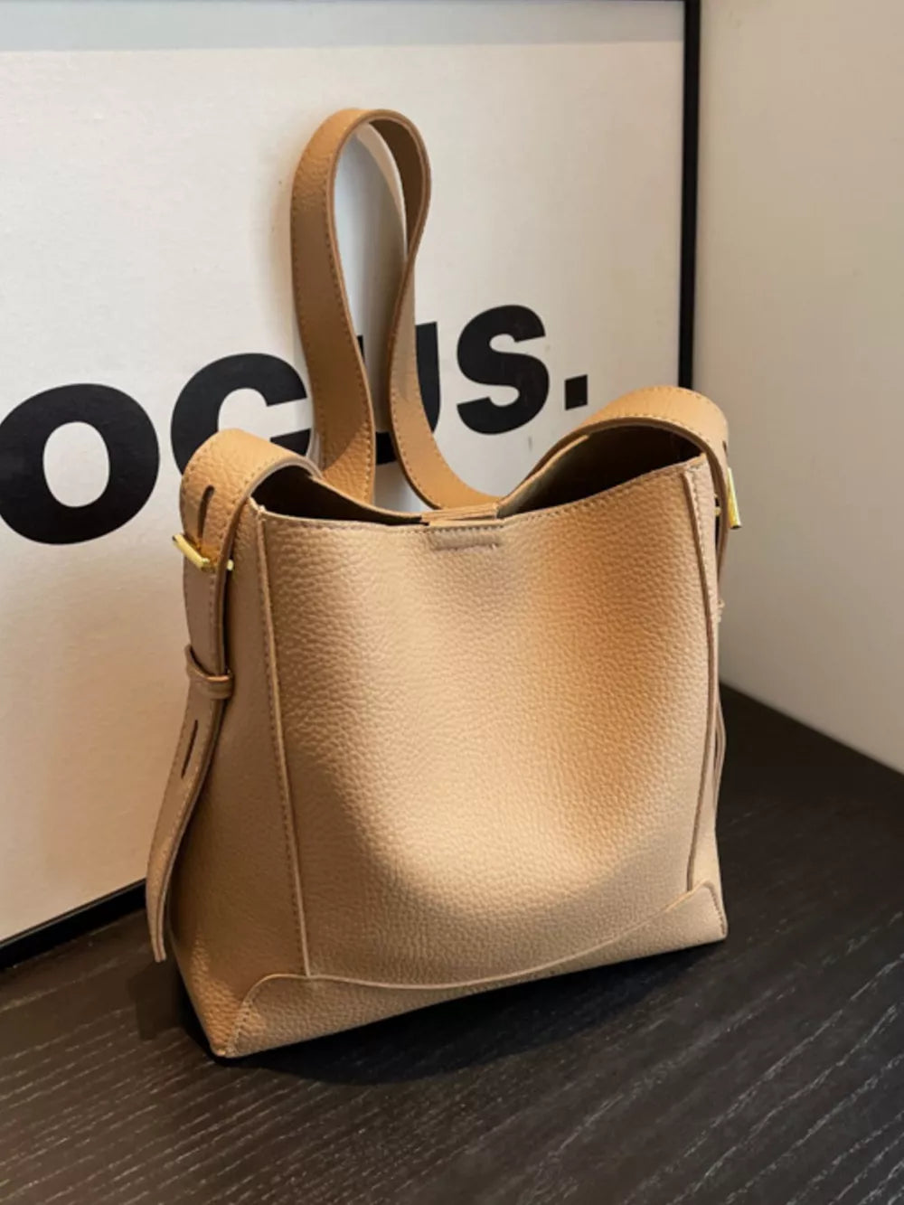 Khaki pebbled leather crossbody bag with adjustable strap and gold buckle detail.