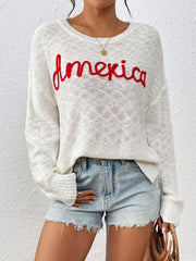Ivory knit sweater with red embroidered "America" text, crew neck, long sleeves.