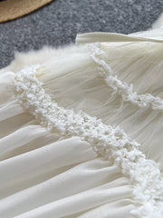 White tiered lace midi maternity dress with textured trim and bow detail.