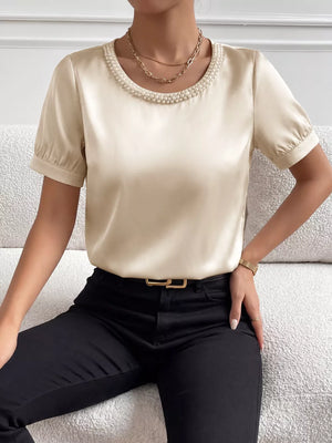Pearl-trimmed satin bodysuit with short puff sleeves and a round neckline.