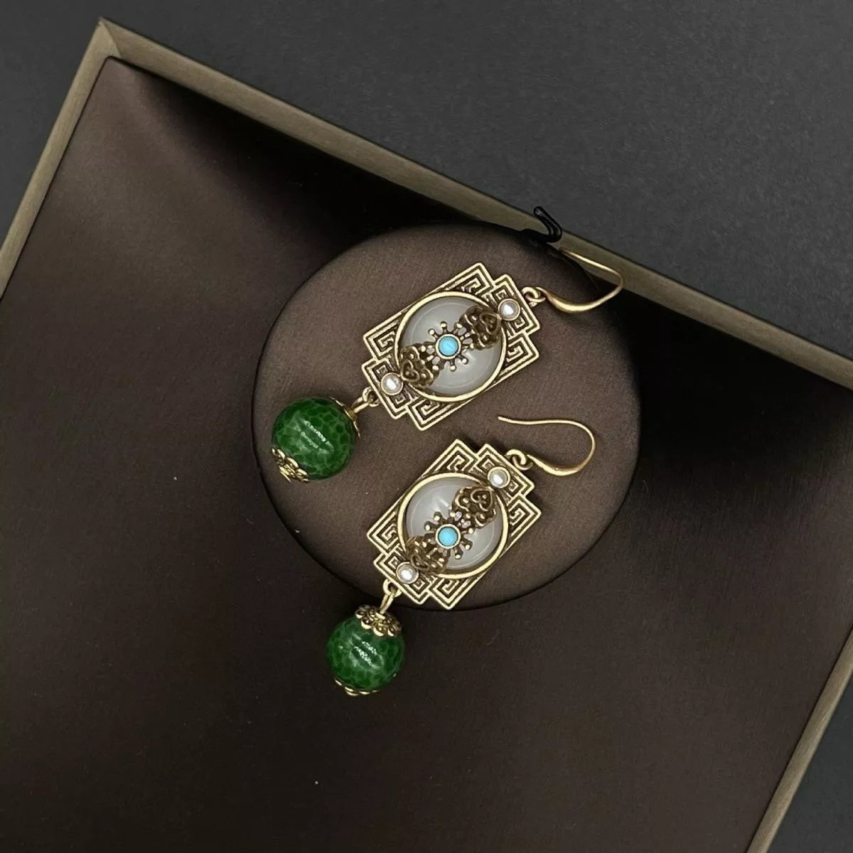 Vintage gold-plated dangle earrings with dark green beads and white stone accents.