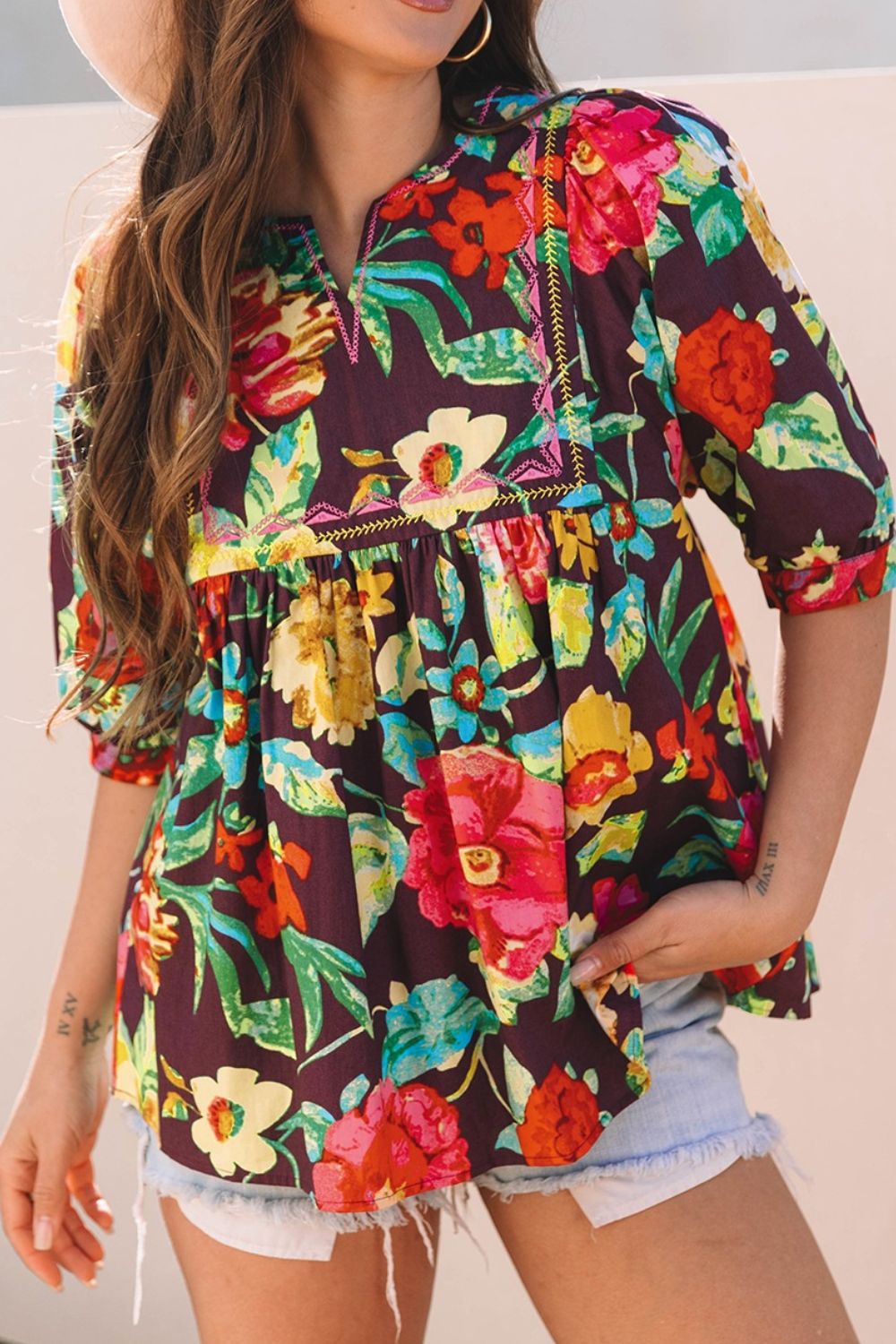 Embroidered floral babydoll blouse with split neck and puff sleeves.