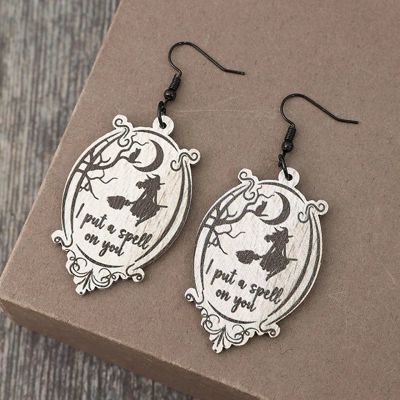 Black wood drop earrings with witch and moon design, saying I put a spell on you