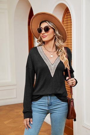 Black relaxed knit sweater with lace-trimmed V-neck and long sleeves.