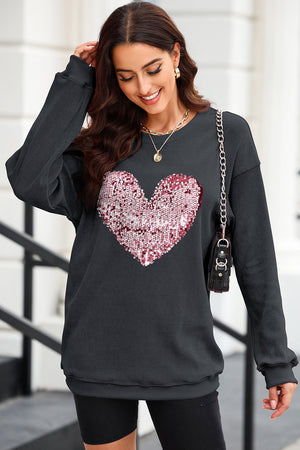 Black ribbed knit sweatshirt with a pink and white sequin heart detail.
