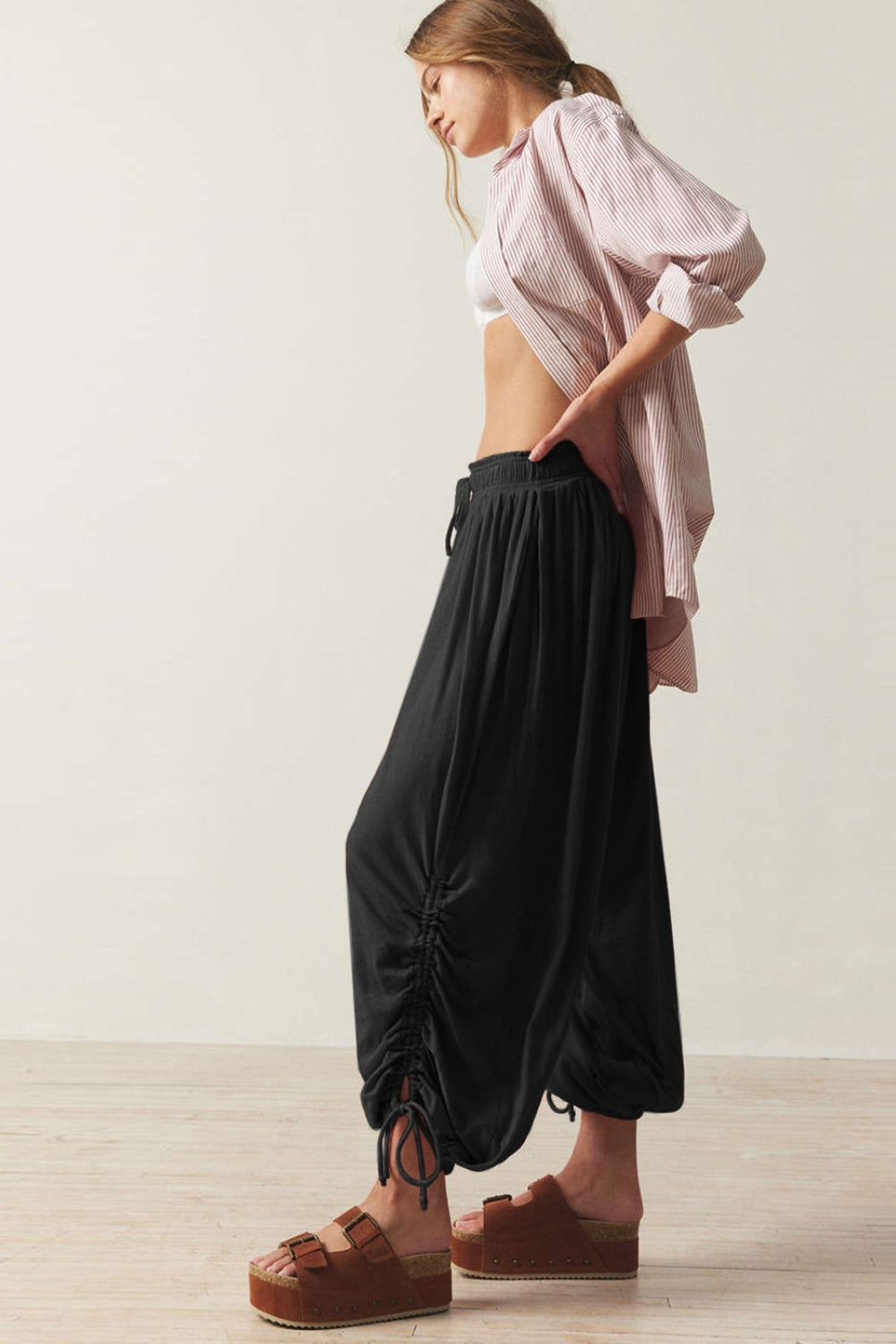 Black gathered ankle-tie balloon trousers with drawstring waist and ruched detailing.