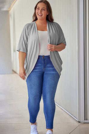 Light gray ribbed batwing cardigan with drape front, worn over a white tank top and blue jeans.