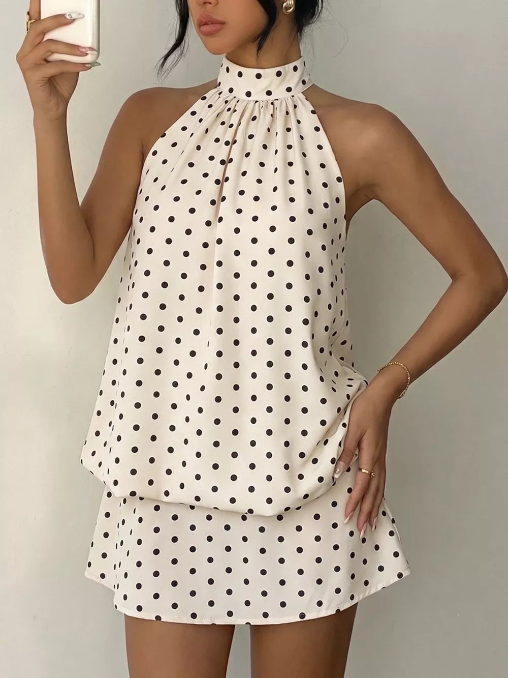 Chic polka dot halter mini dress in apricot with a gathered neckline and A-line skirt.