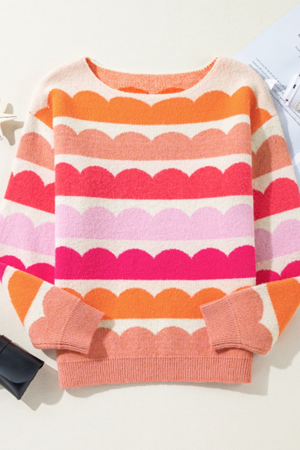Scalloped stripe off-the-shoulder sweater in pink, orange, and white acrylic knit.