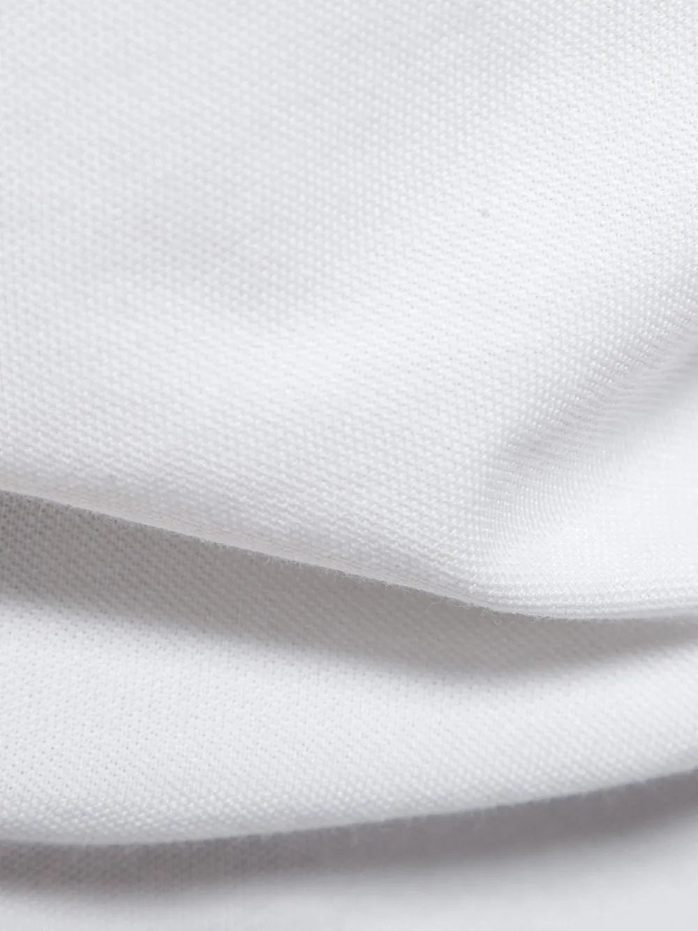 White piqué polo shirt fabric detail showing textured weave