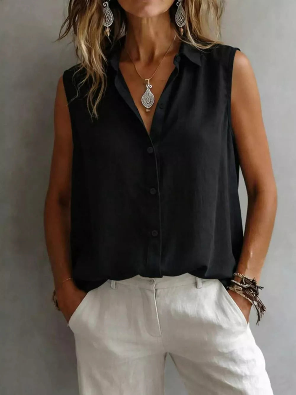 Black sleeveless button-up shirt with a collared neckline and button closure.