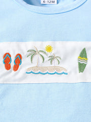 Baby blue cotton t-shirt with embroidered beach scene, flip flops, palm trees, sun, and surfboard.
