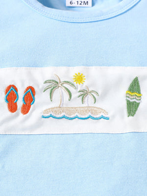 Baby blue cotton t-shirt with embroidered beach scene, flip flops, palm trees, sun, and surfboard.
